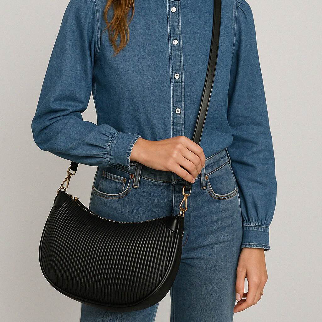 Black crescent moon wavy PU crossbody bag with gold hardware, worn by a model in denim.