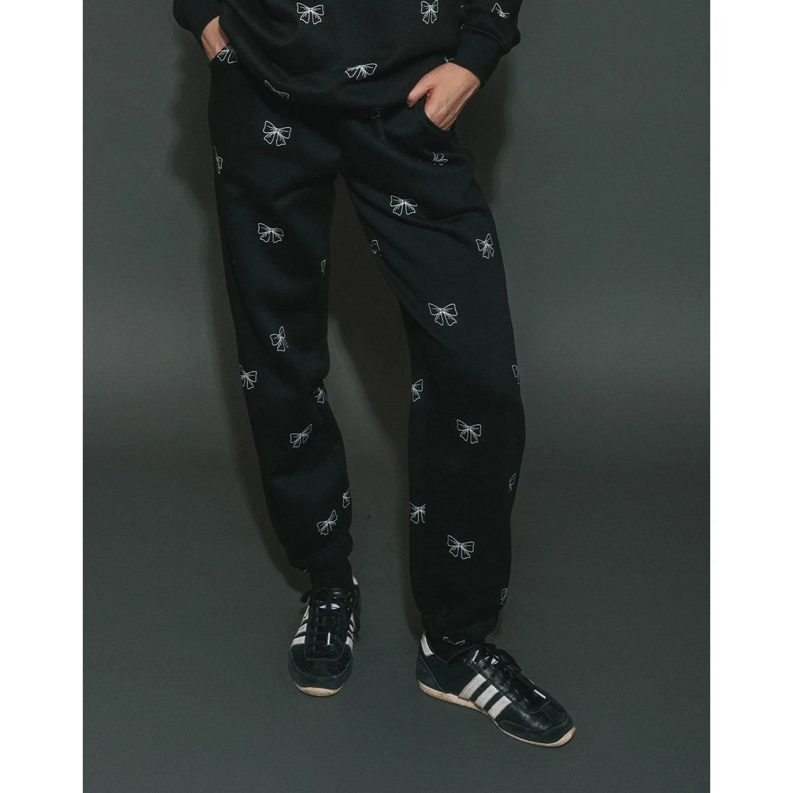 Brunette the Label All Over Bow Best Friend Jogger in black with scattered white bow prints, paired with sneakers.