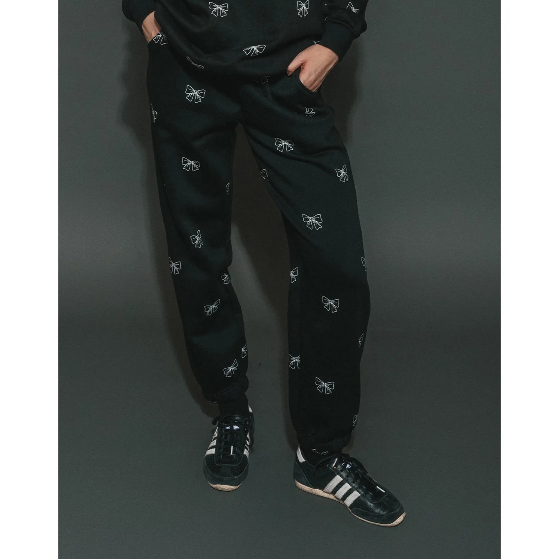 Brunette the Label All Over Bow Best Friend Jogger in black with scattered white bow prints, paired with sneakers.