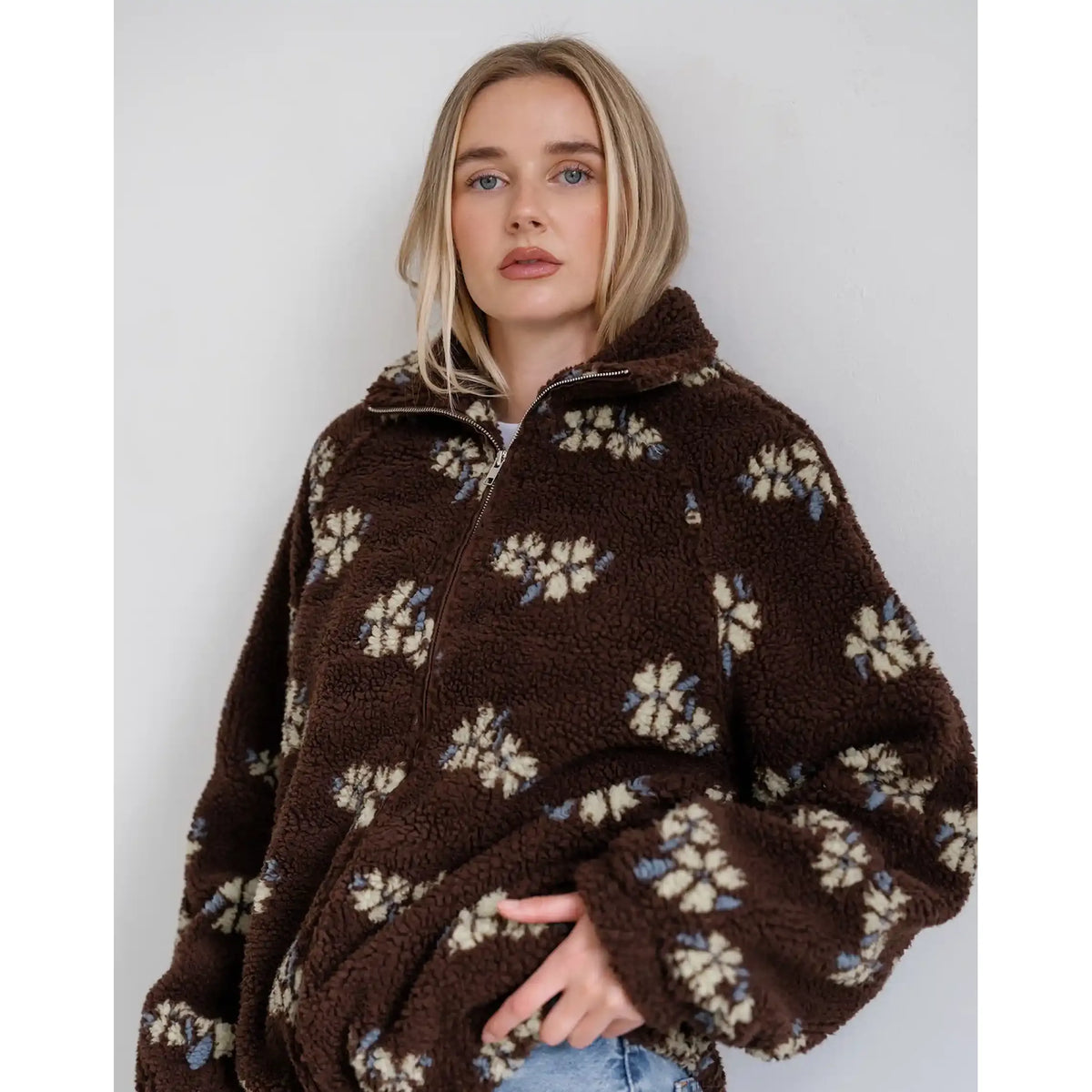 Brown sherpa jacket with cream and blue horse print, featuring a relaxed fit, full zip, and cozy collar.