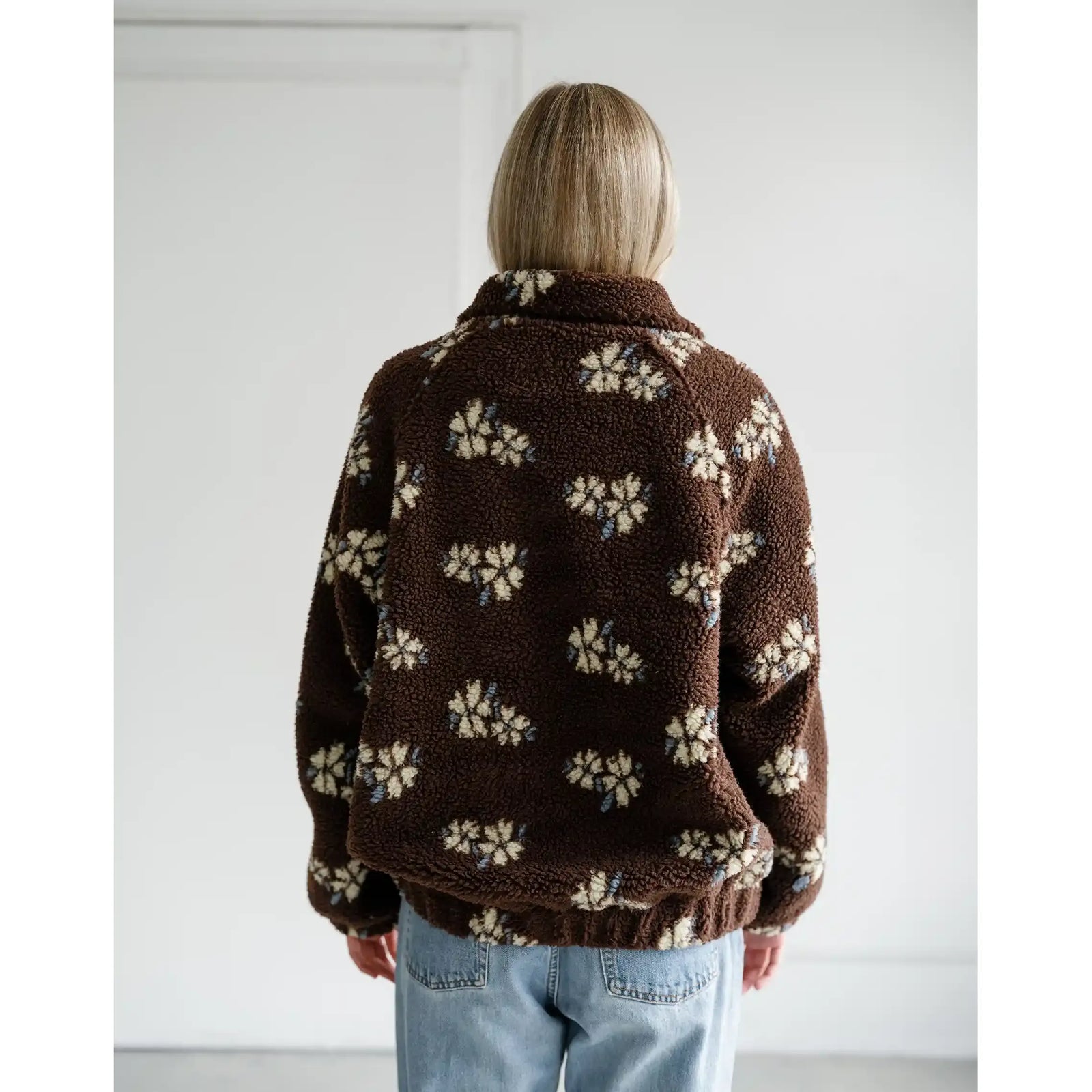Back view of a brown Sherpa jacket with an all-over cream horse print, featuring a cozy collar and relaxed fit.