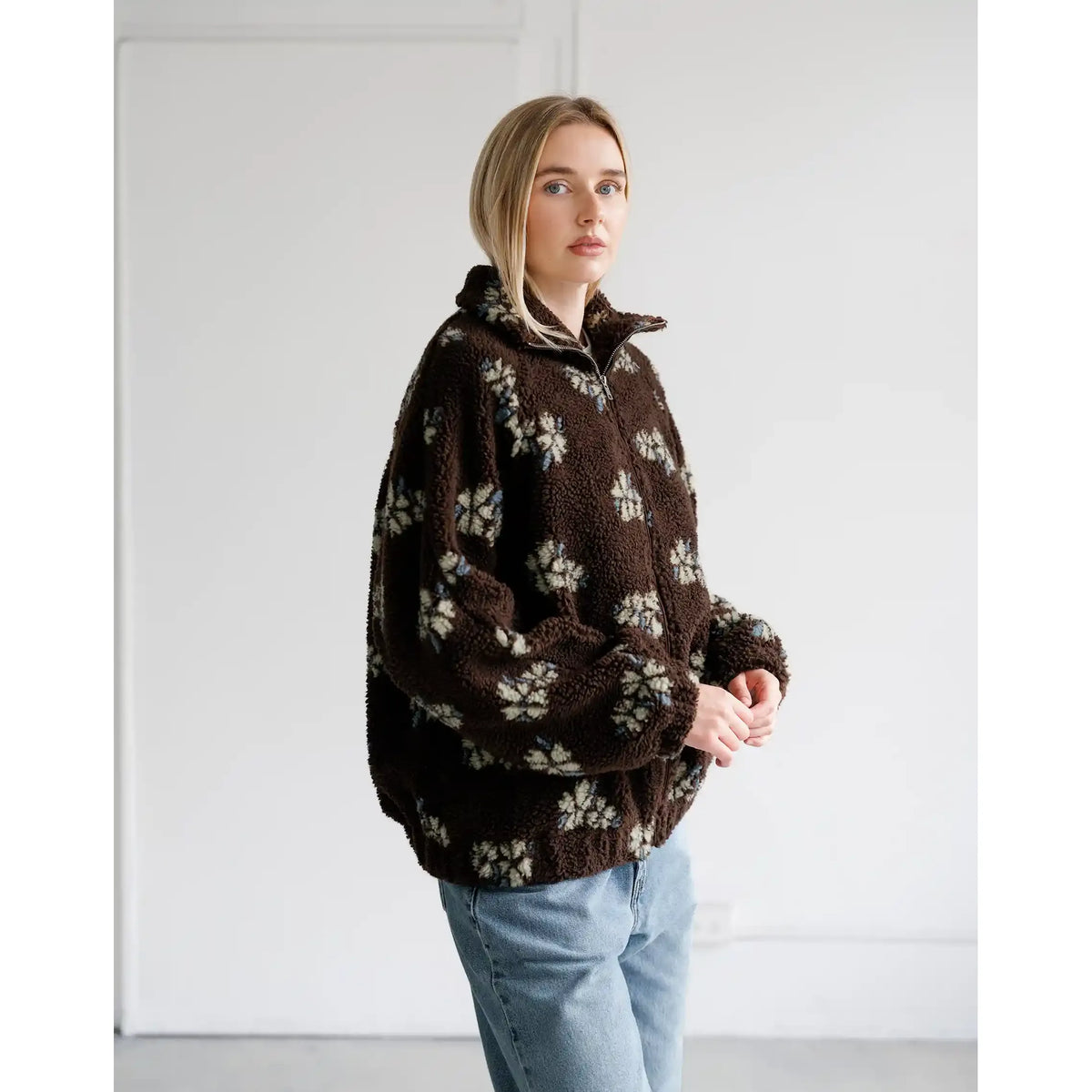 Brown sherpa jacket with all-over horse print, relaxed fit, full zip, and cozy collar.