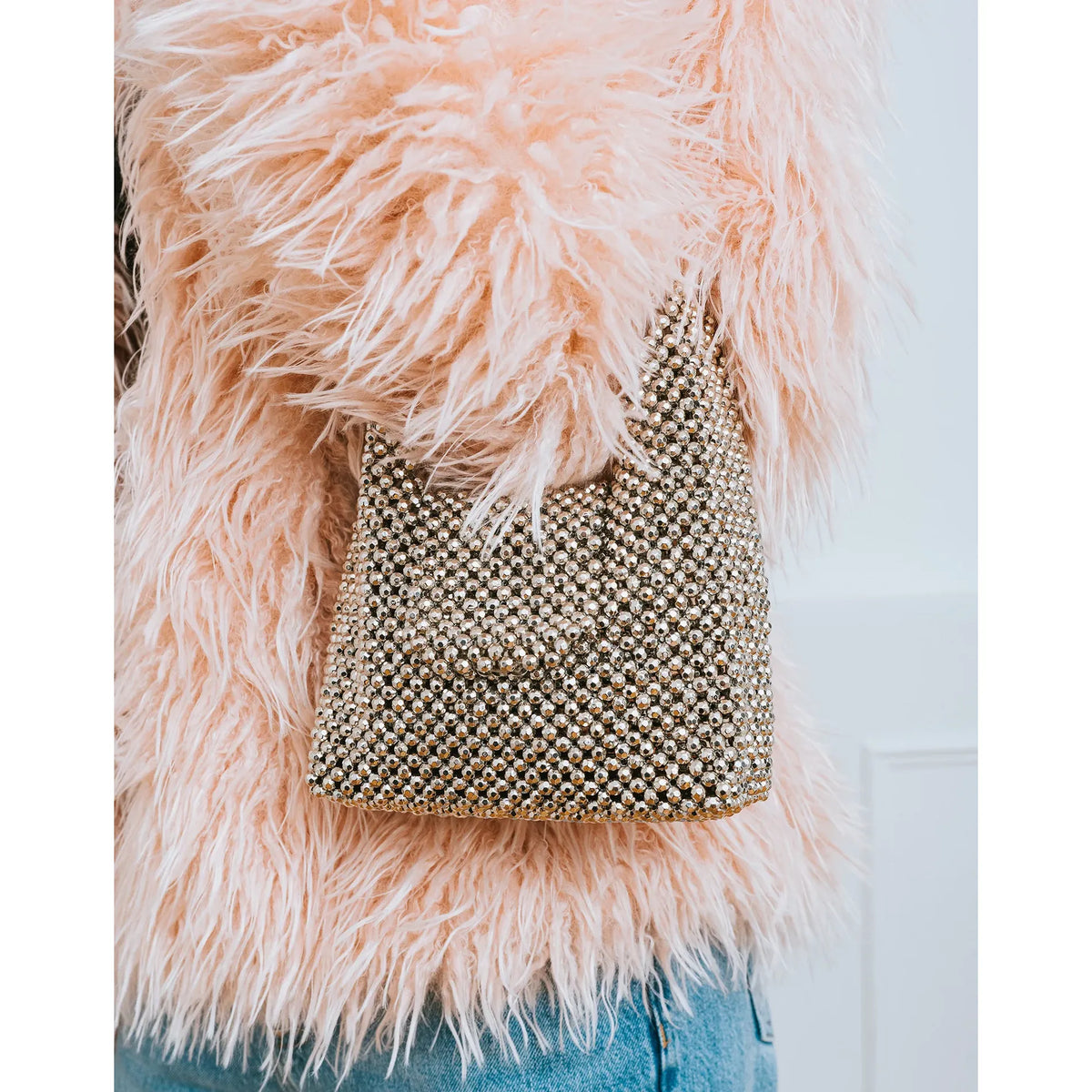 Brunette the Label Crystal Hand Bag adorned with crystals that refract light, paired with a pink faux-fur coat.