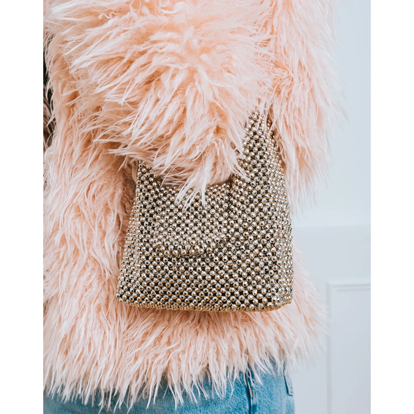 Brunette the Label Crystal Hand Bag adorned with crystals that refract light, paired with a pink faux-fur coat.