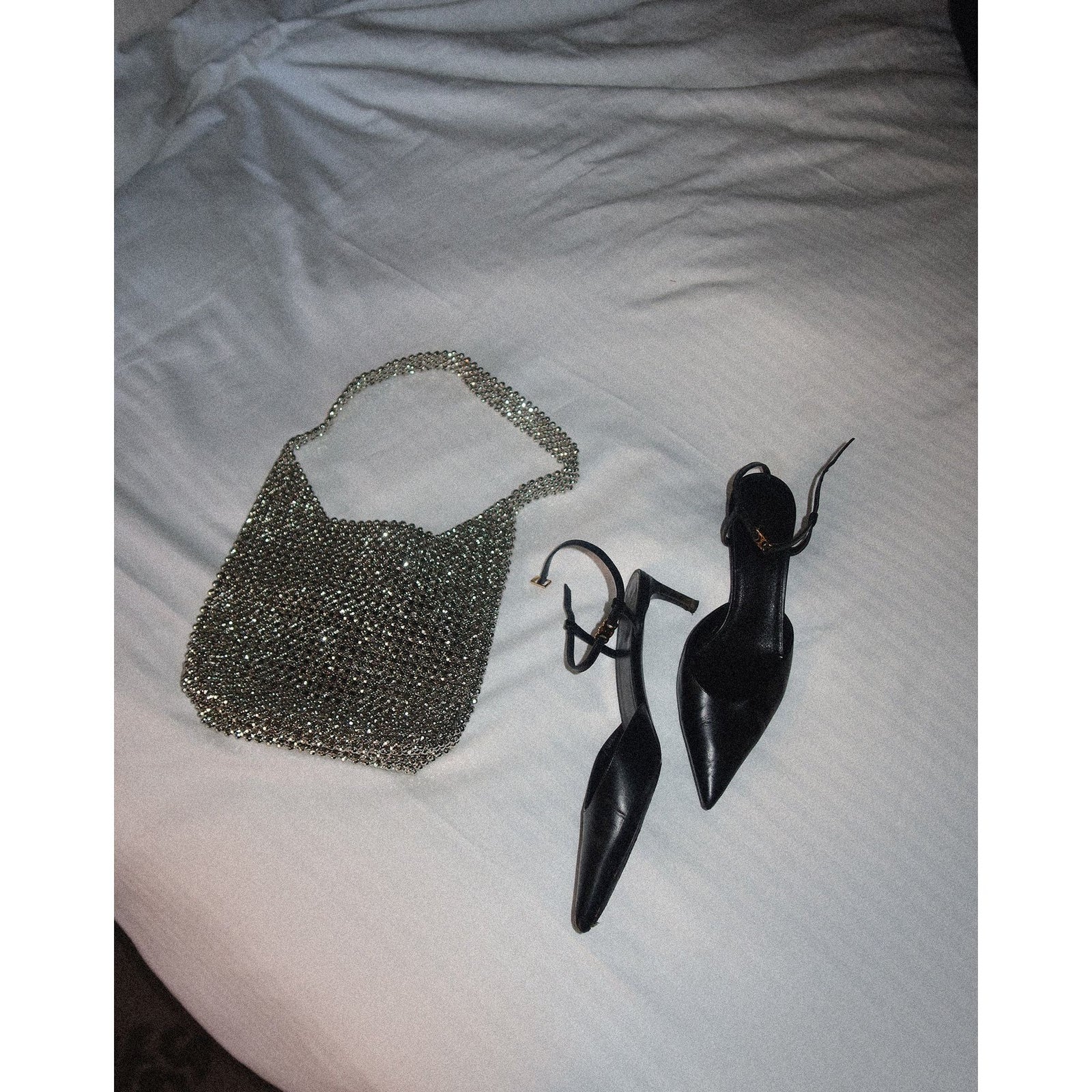 Brunette the Label crystal pouch bag with hand-placed crystals beside black pointed-toe stilettos.