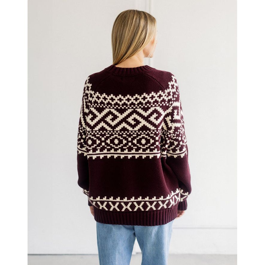 Back view of a deep plum oversized Fair Isle knit sweater featuring bold cream geometric patterns across the back and sleeves.