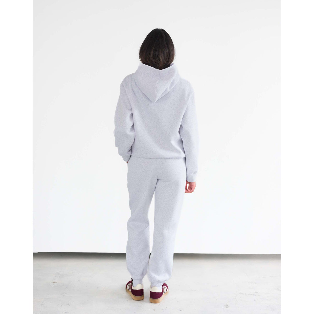 Back view of a model wearing Brunette the Label Kind Club Core Hoodie in light gray with matching joggers.
