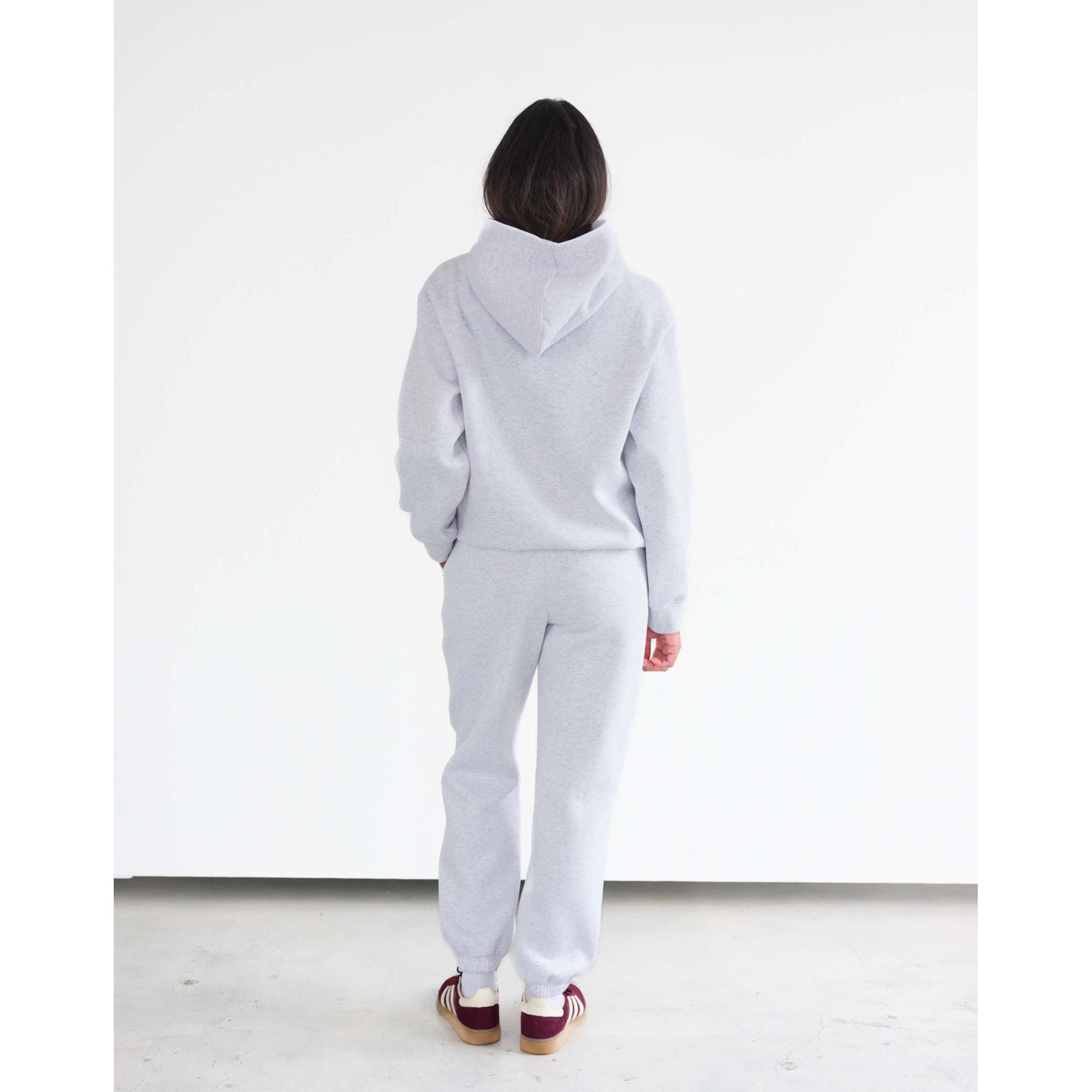 Back view of a model wearing Brunette the Label Kind Club Core Hoodie in light gray with matching joggers.