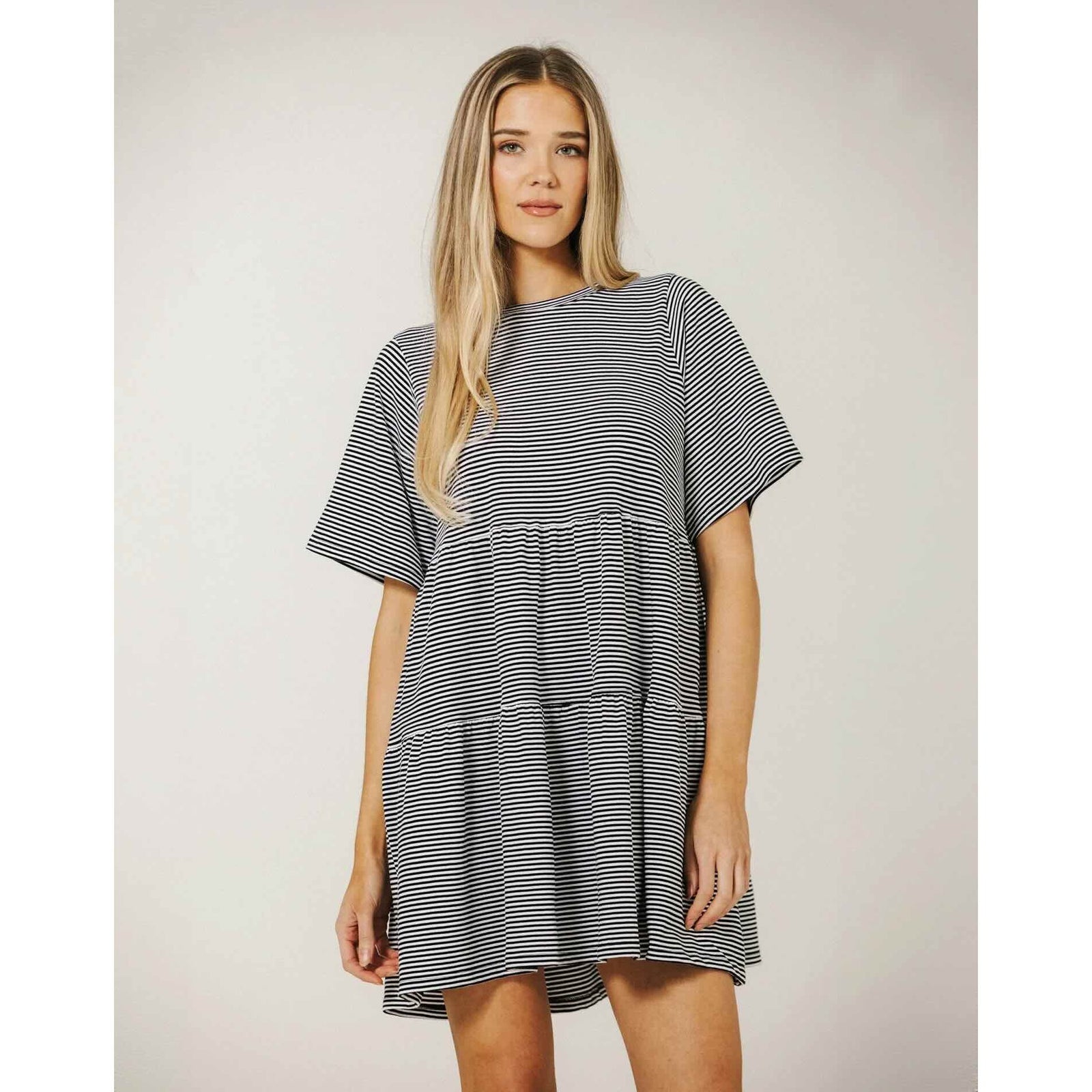 Model wearing Brunette The Label Tiered Dress, black-and-white striped, oversized short-sleeve.