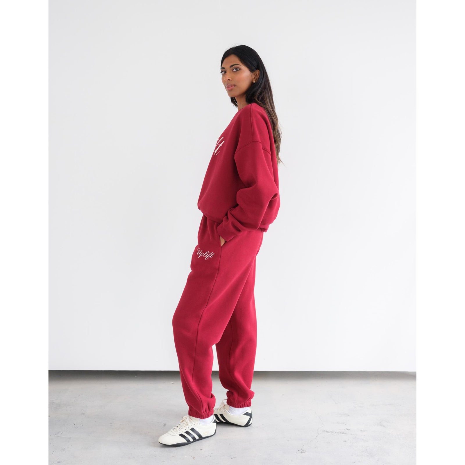 Woman wearing Brunette the Label Uplift Perfect Crew red cotton-terry lounge set with 'Uplift' script on front.
