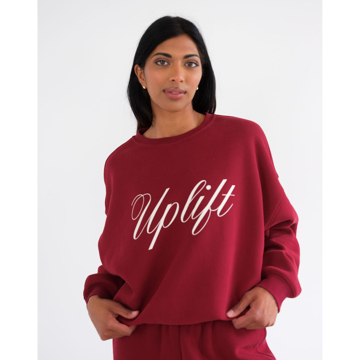 Brunette the Label Uplift Perfect Crew sweatshirt in burgundy with white cursive &#39;Uplift&#39; on front, worn by a model.