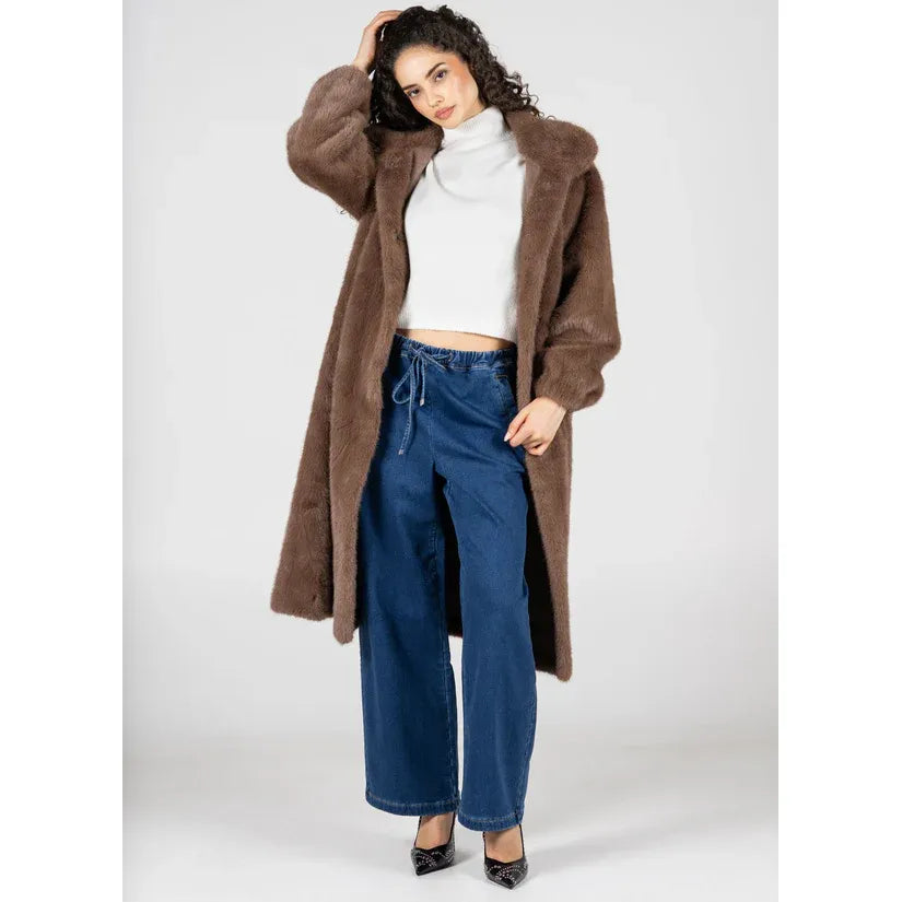 C'est Moi brown faux-fur long coat with lapel collar and snap buttons, elastic sleeves, over white top and blue jeans.