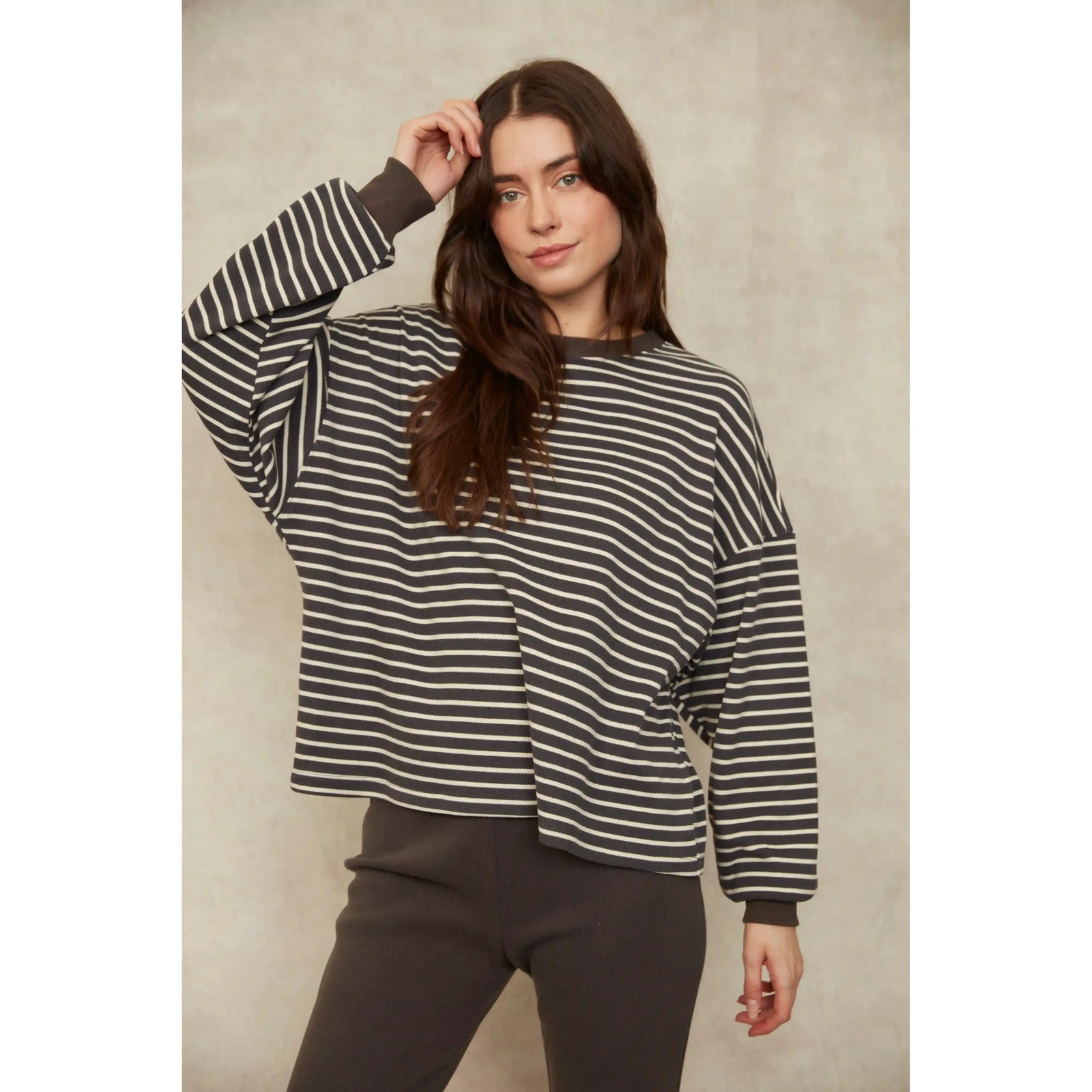 Woman wearing a relaxed fit long sleeve striped waffle top with classic horizontal detailing in dark grey and off-white.