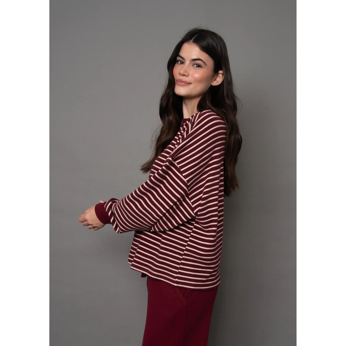 Woman wearing a burgundy and cream striped waffle knit top with long sleeves and relaxed fit.