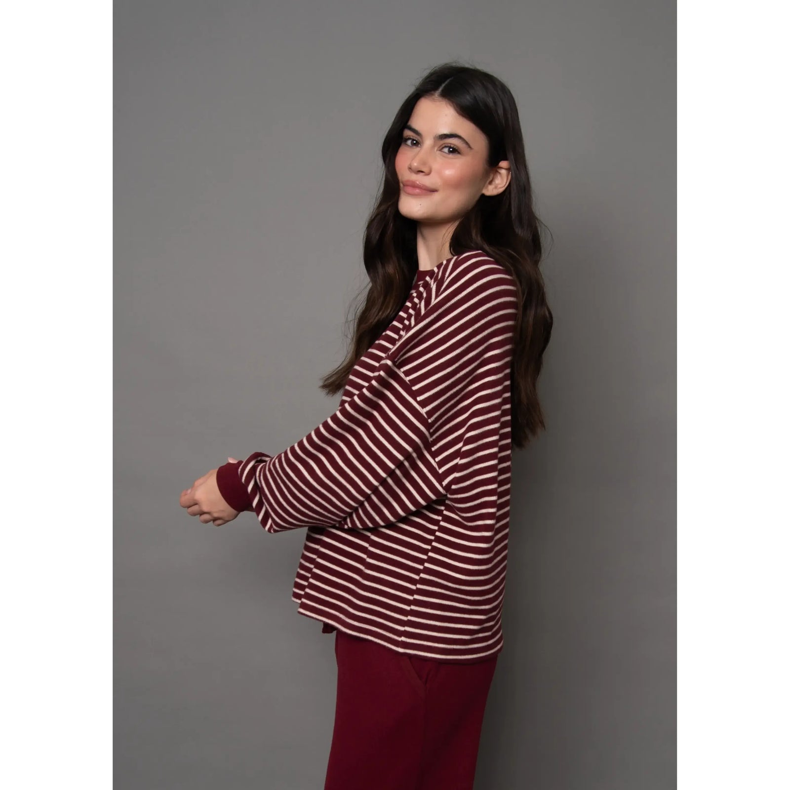 Woman wearing a burgundy and cream striped waffle knit top with long sleeves and relaxed fit.