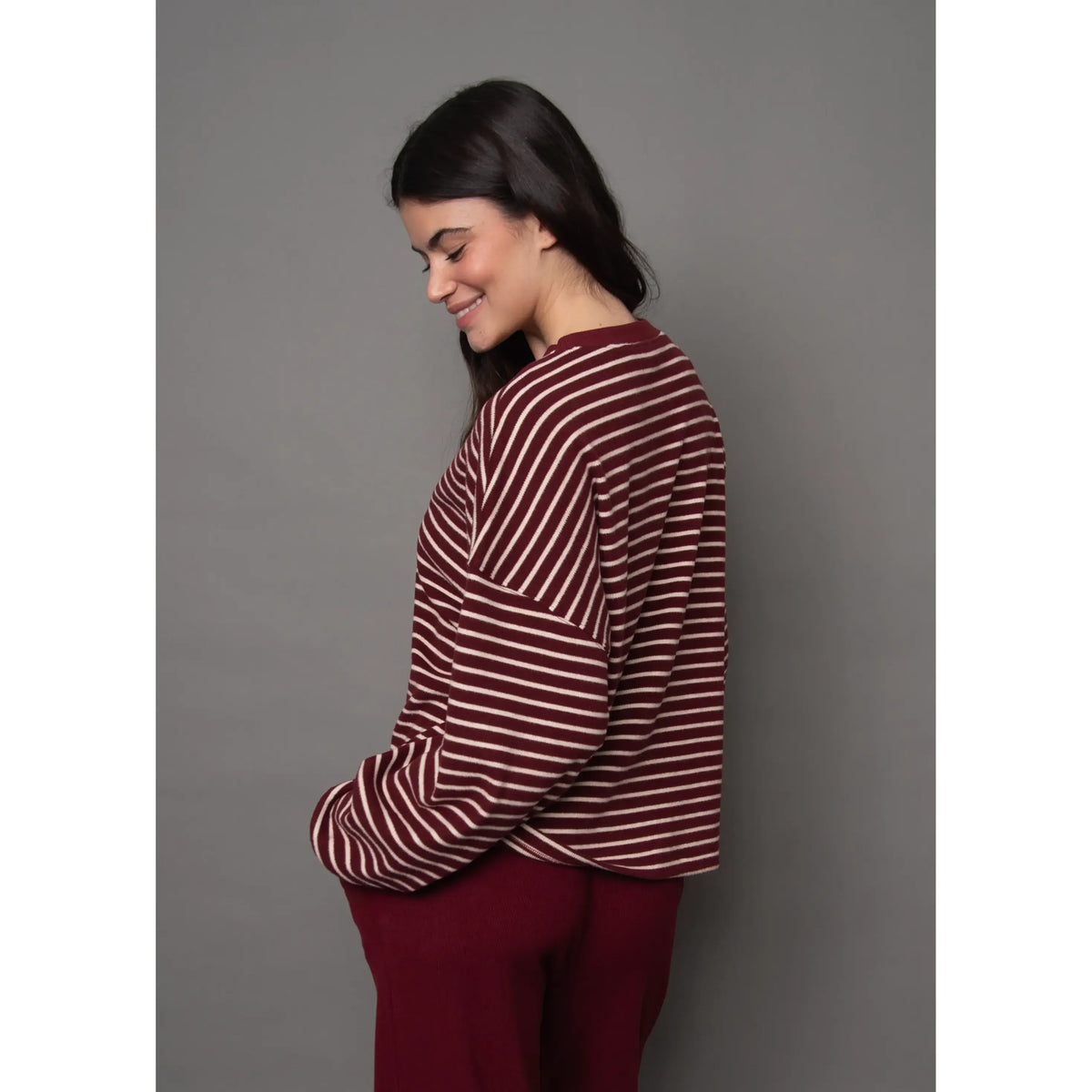 Woman wearing burgundy and cream striped waffle knit top with relaxed fit and horizontal stripes.