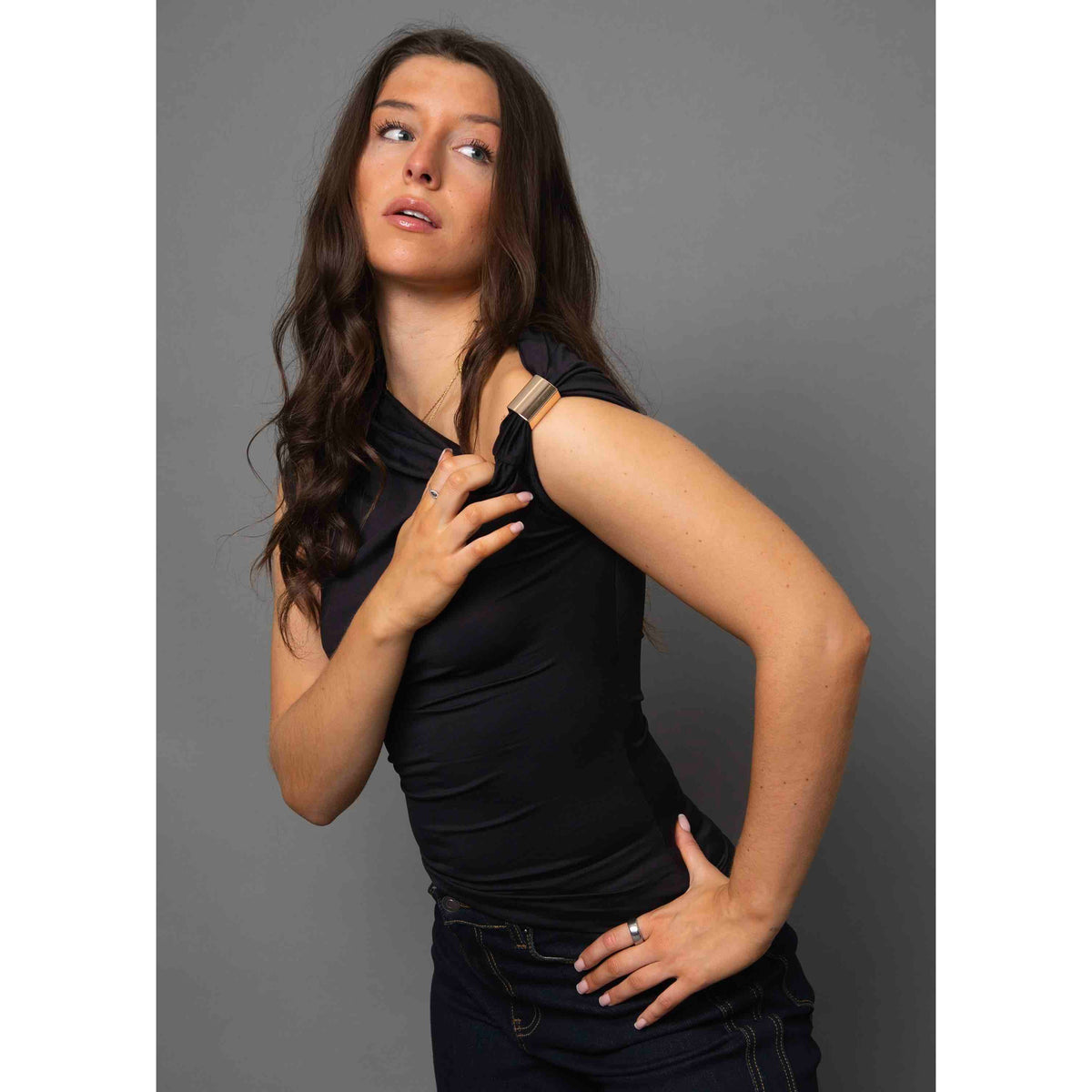 Damian Asymmetric Top on a model: black sleeveless one-shoulder top with gold hardware, versatile from casual to chic.