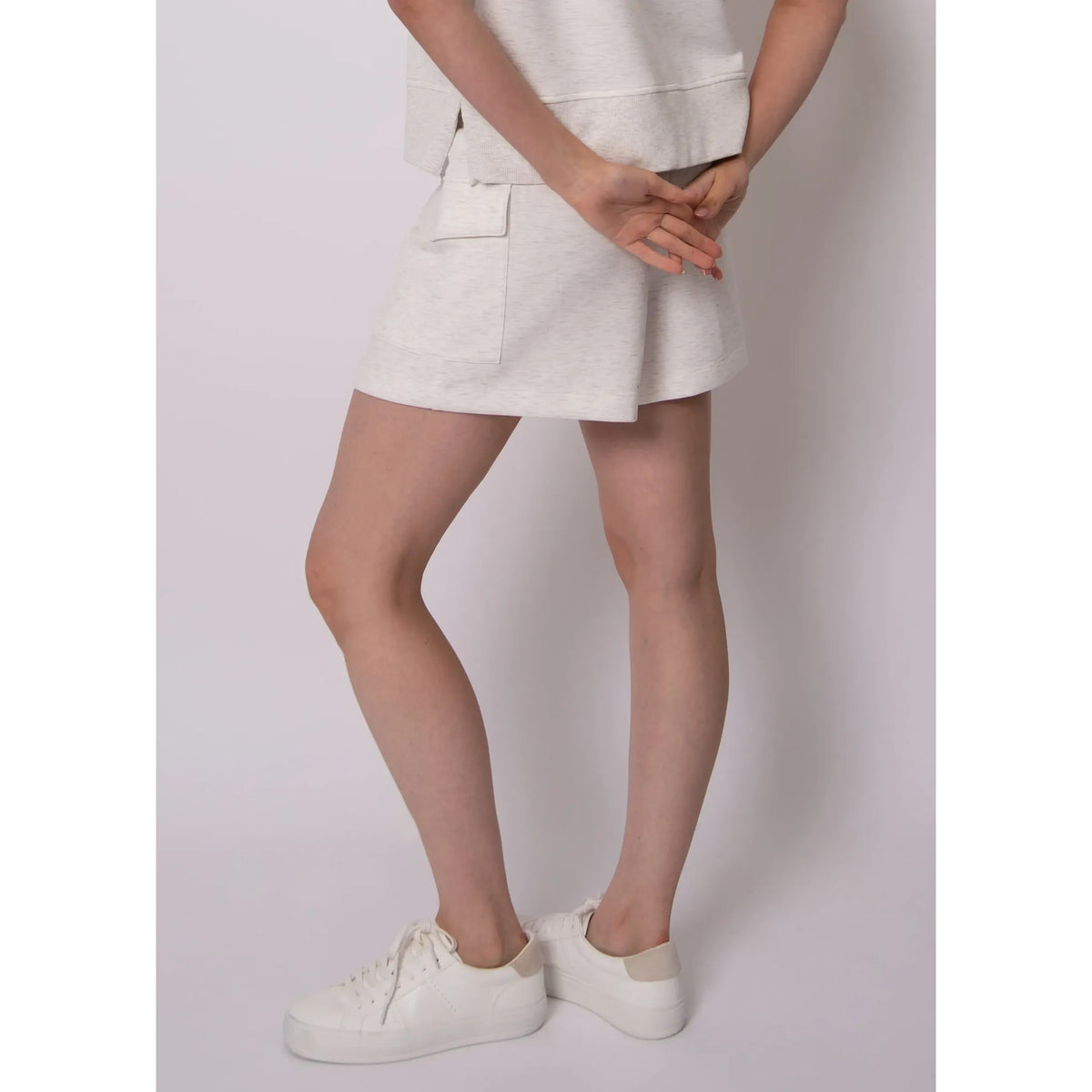 Darcia Soft Knit Drawstring Shorts in light heathered ivory with back pocket on model, paired with white sneakers.