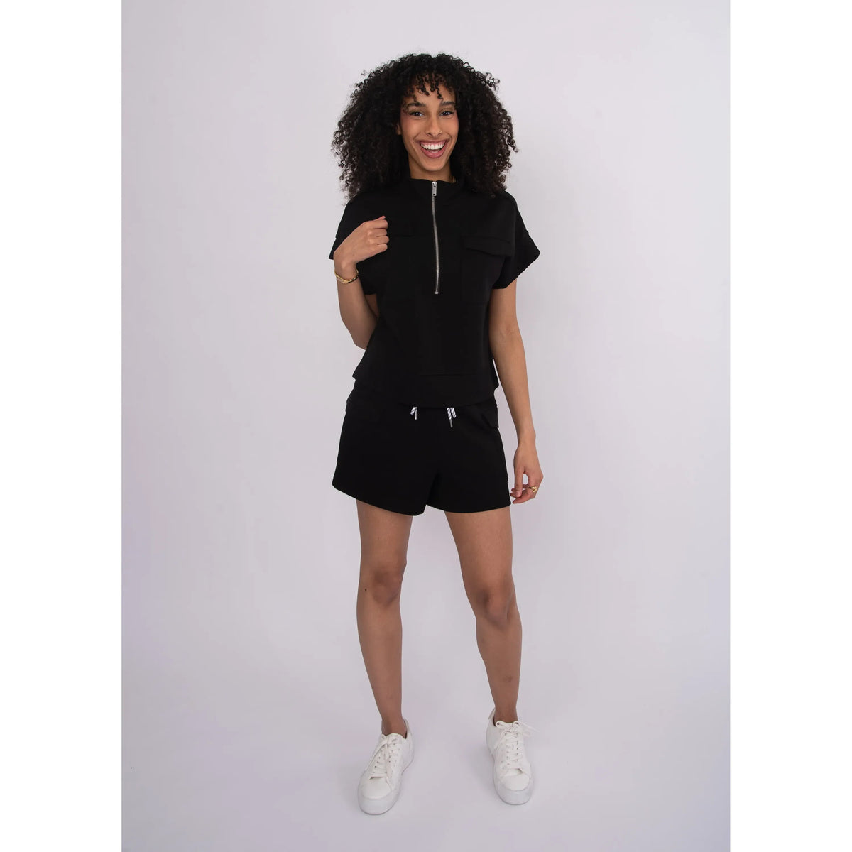 Model wearing black Darcia Soft Knit Drawstring Shorts with drawstring waist, paired with white sneakers.