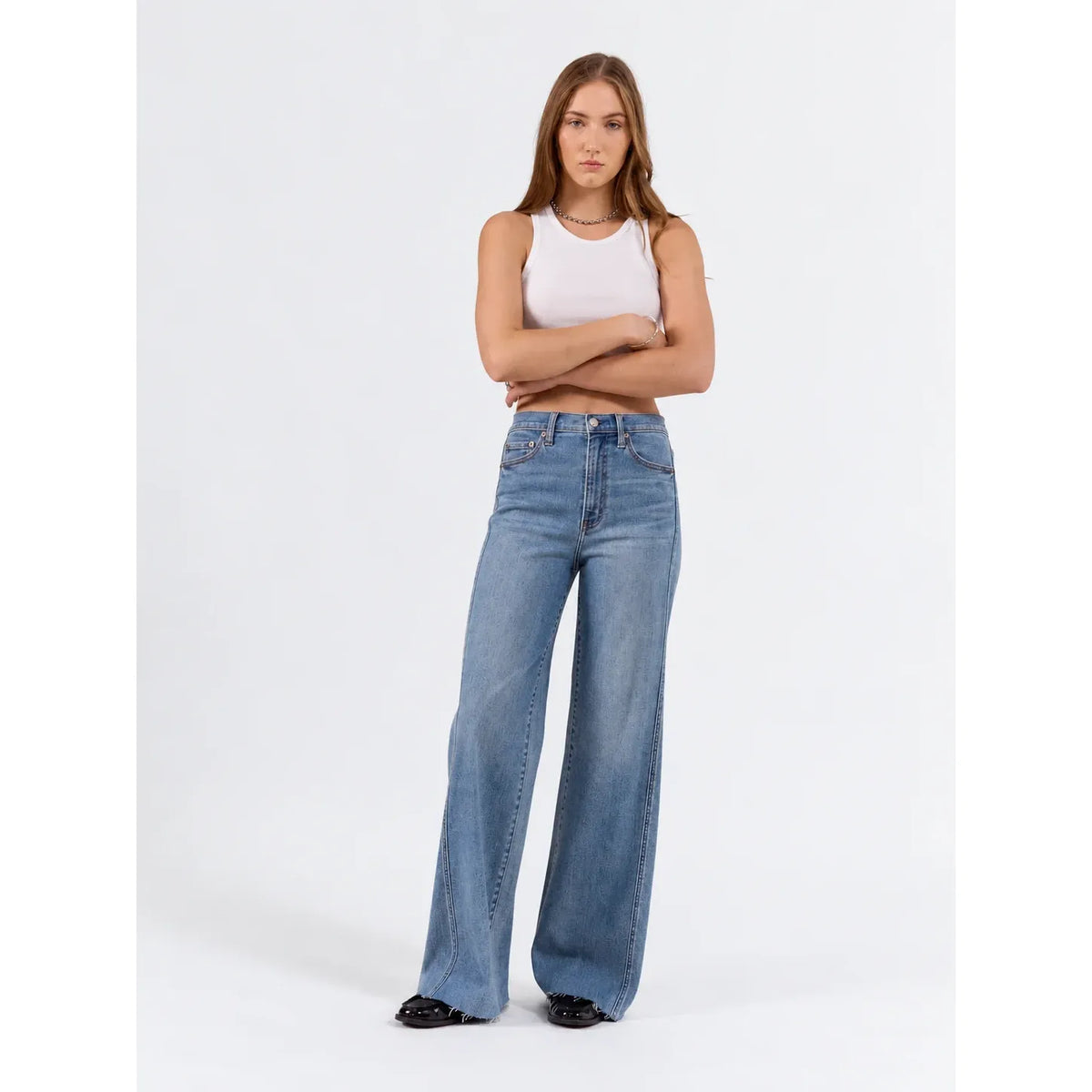 Model wearing high-rise wide-leg jeans in vintage medium wash with paneled seams and raw hem.