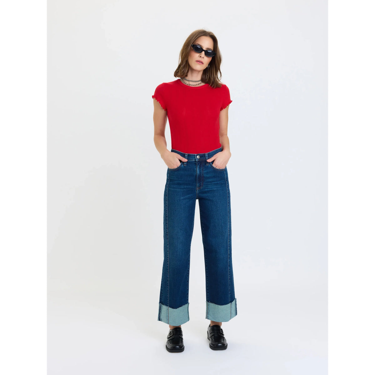 High rise wide leg ankle jeans in dark wash denim with fading and large rolled cuffs, styled with a red top and black loafers.