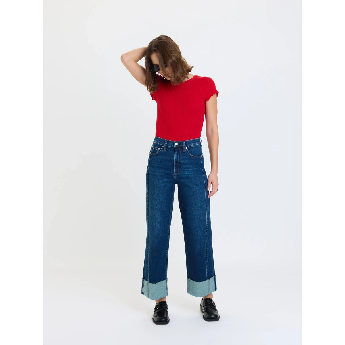 High rise wide leg ankle jeans with vintage fading and exposed seam details, styled with a red top and black shoes.