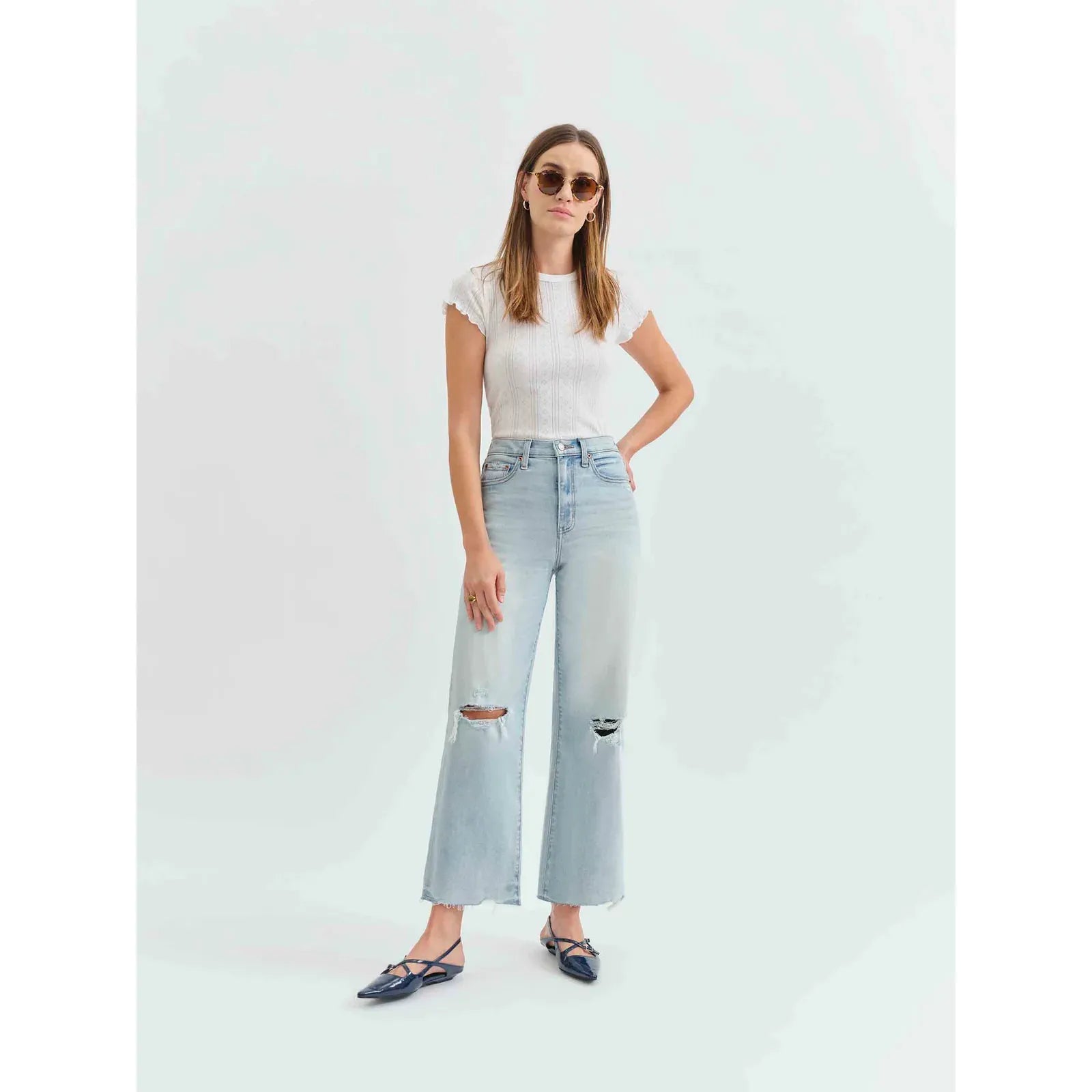 Stylish woman wearing Daze Pleaser High Rise Wide Leg Ankle in Charisma, featuring distressed details and a vintage wash.