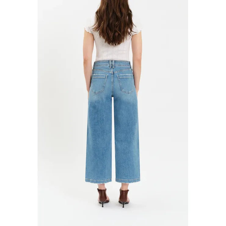 Back view of model in Daze Valley Girl Wide Leg Ankle jeans in Fave, white top, brown boots.
