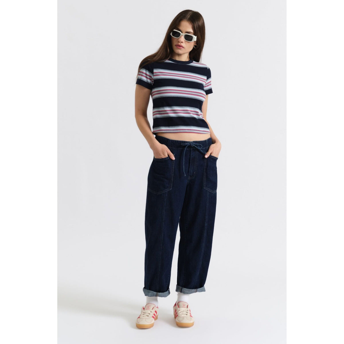 Model wearing Daze Villa Drawstring Barrel pants in Blue Mood with a striped top and white sneakers.