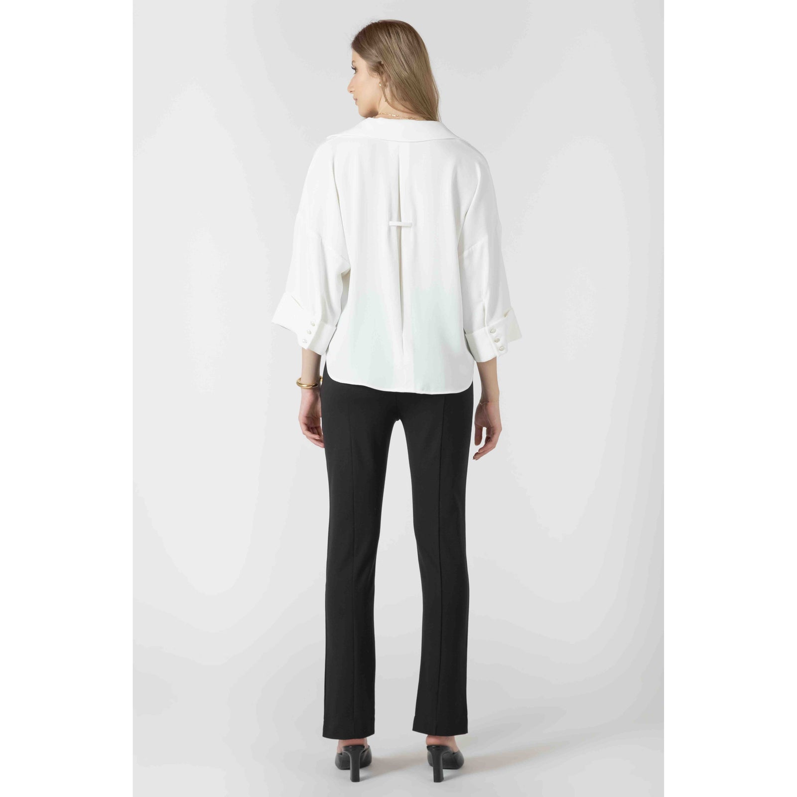 Model wearing white cuffed button-front blouse with wide sleeves and rolled cuffs.