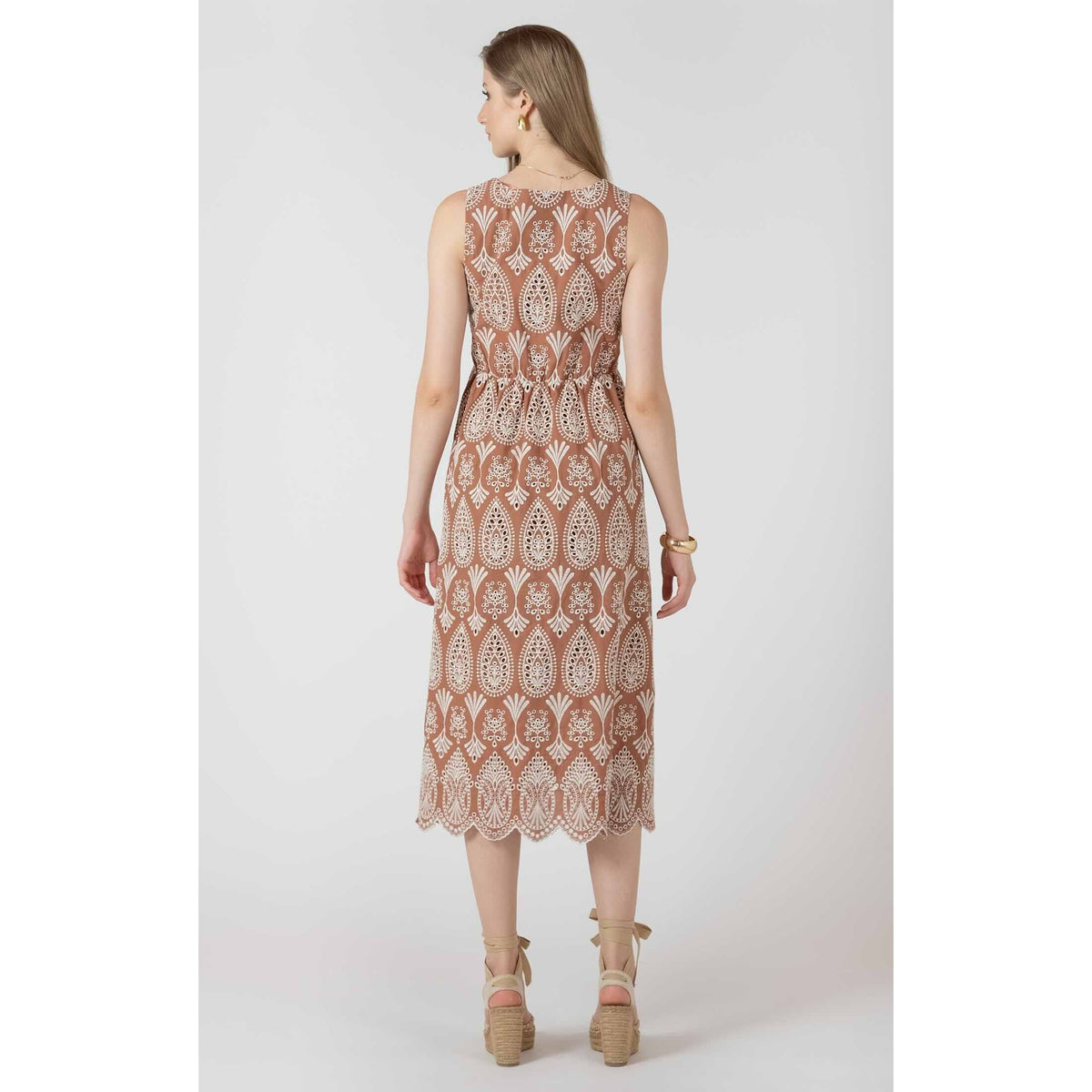Dex Black Tape V Neck Eyelet Dress on model, back view in brown fabric with white eyelet pattern and scalloped hem.