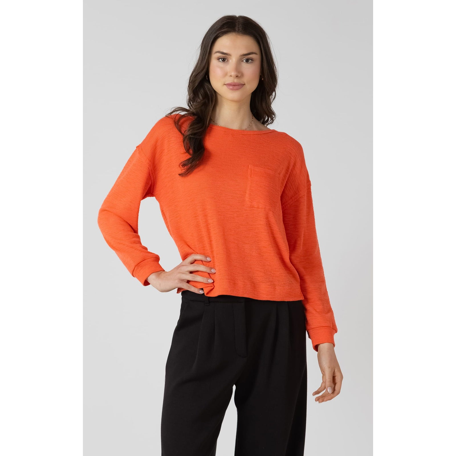 Dex Crewneck Sweatshirt in bright orange, lightweight long-sleeve with chest pocket, worn by model.