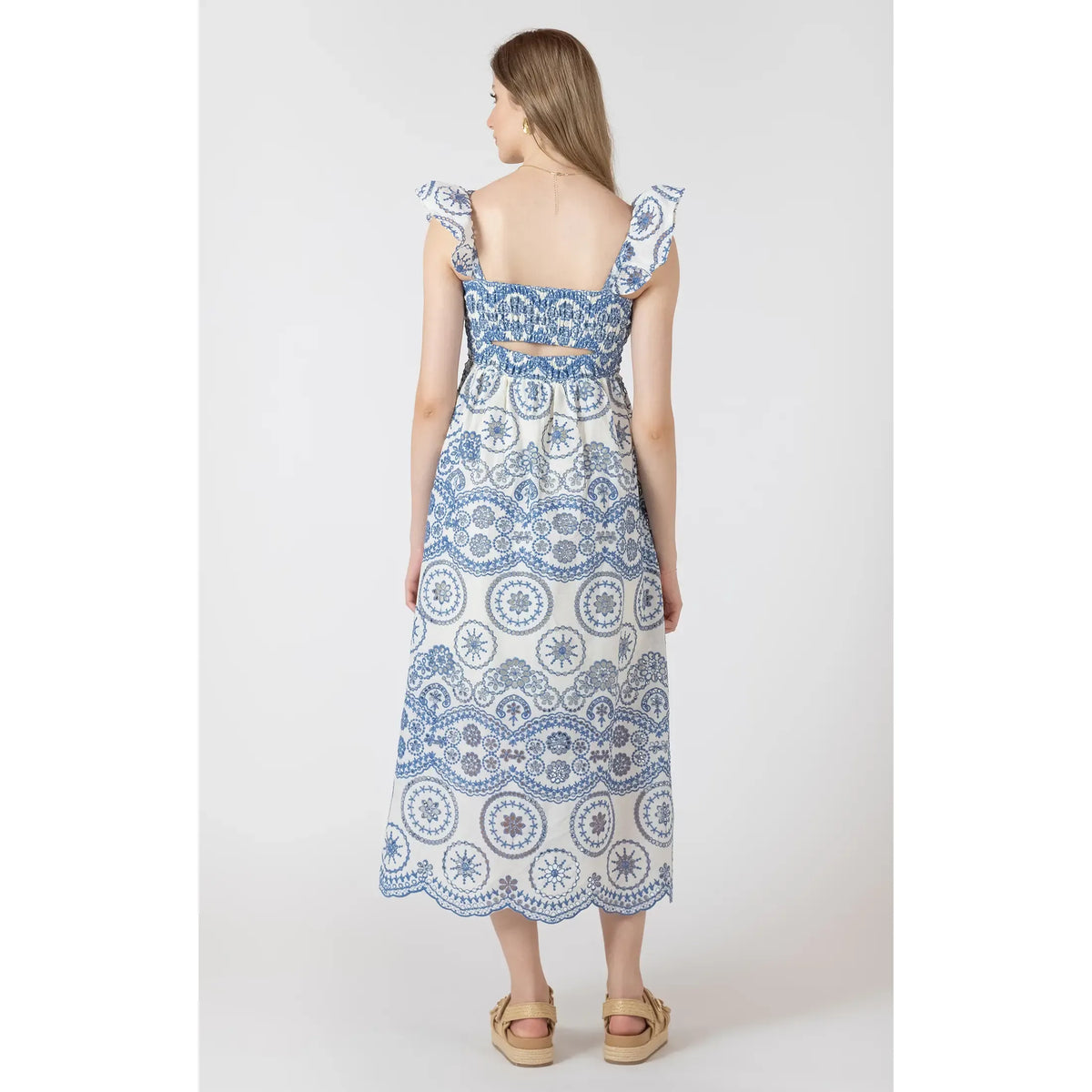 Model wearing Dex V Cutout Embroidered Dress; blue-and-white printed maxi with V-waist and flutter sleeves.