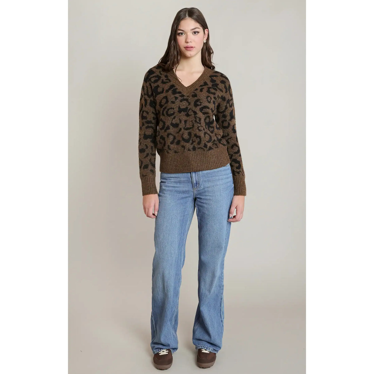 Brown and black leopard print V-neck sweater with long sleeves and ribbed hem, styled with blue jeans.