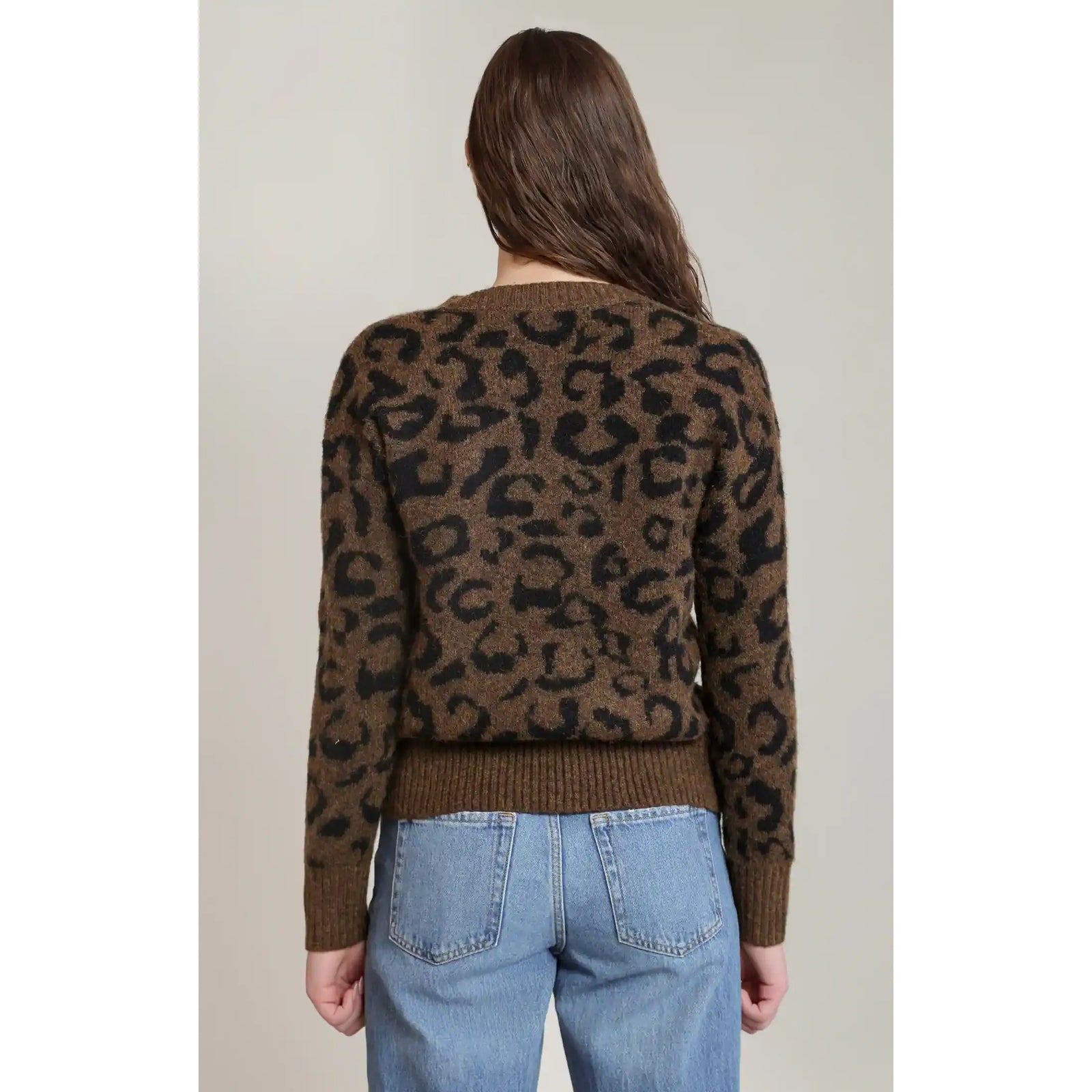 Back view of a brown and black leopard print V-neck sweater with long sleeves and ribbed hem, paired with blue jeans.