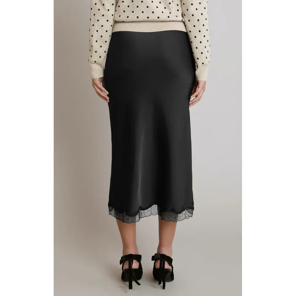 Black satin midi skirt with delicate lace trim hem, featuring a fluid drape and elegant silhouette paired with a polka dot sweater.