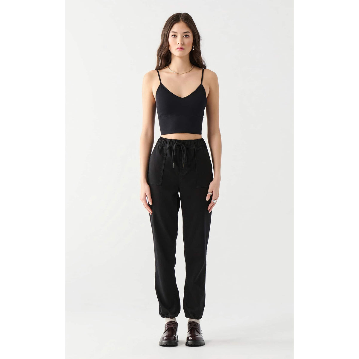 Model wearing Dex Seamless Bra Top, black cotton-spandex cropped top with thin straps.