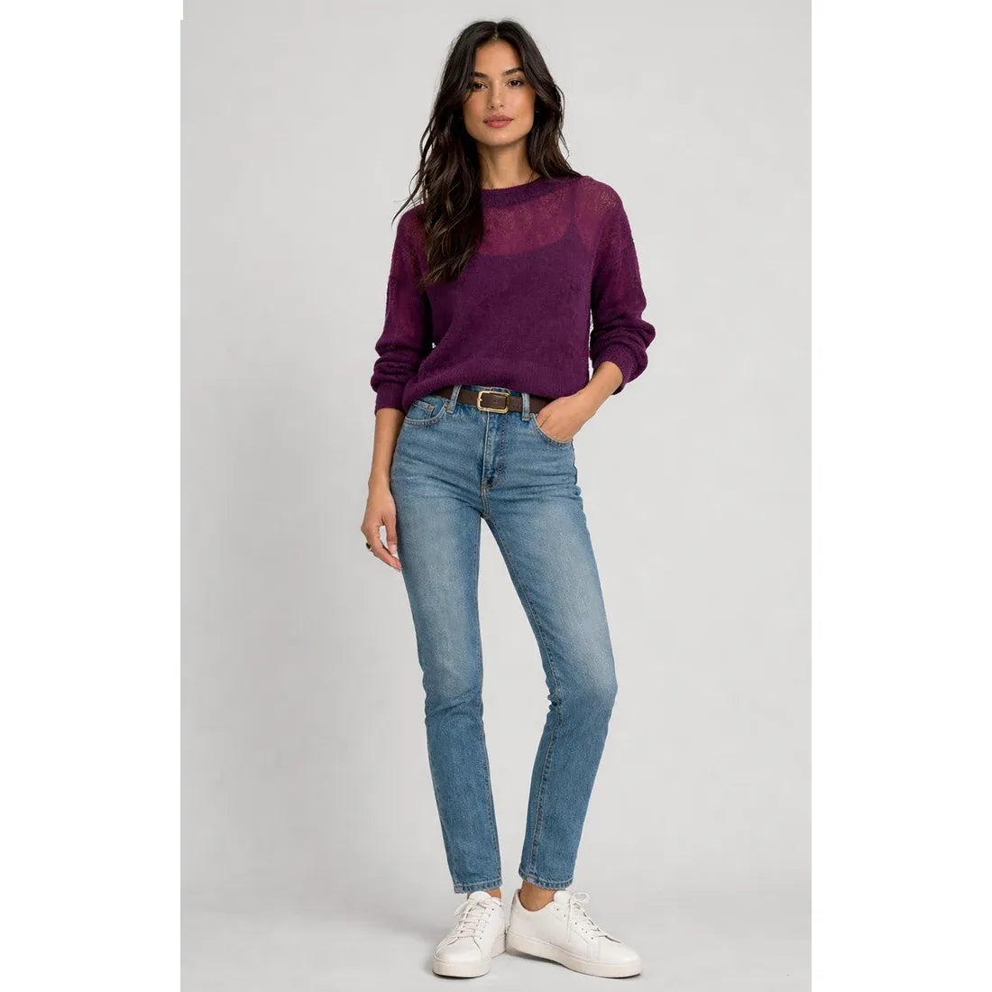 Purple sheer knit sweater top with semi-sheer chest panel layered over a camisole, styled with blue jeans and a brown belt.