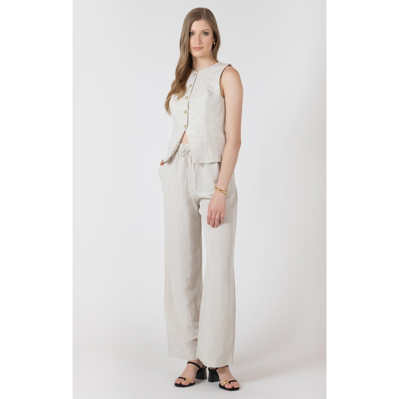 Dex Summer Vest worn by a model; sleeveless beige linen top with a front button placket, paired with matching pants.
