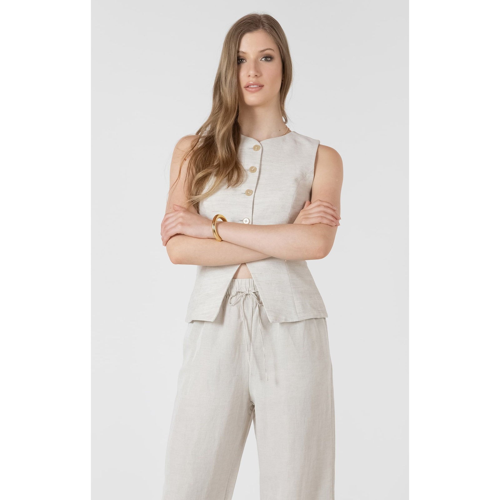 Dex Summer Vest worn by a model; sleeveless beige linen top with a front button placket, paired with matching pants.