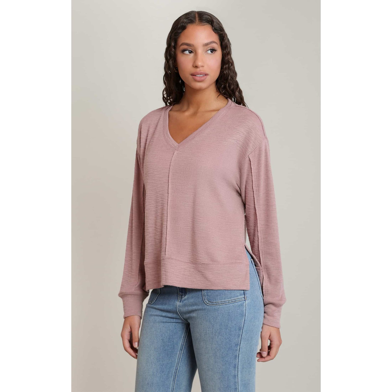 Dex V-Neck Long Sleeve Knit Top in dusty pink with relaxed fit and raw seams, styled with jeans.