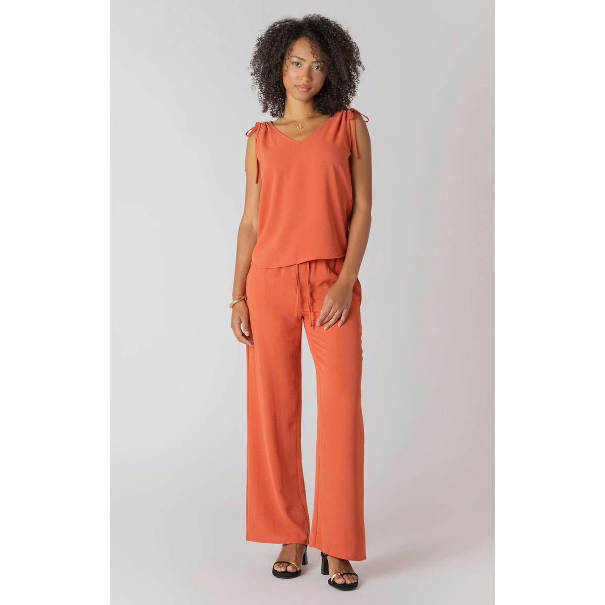 Model wearing Room 34 V-Neck Top with Shoulder Ties in orange, sleeveless with adjustable shoulder ties.