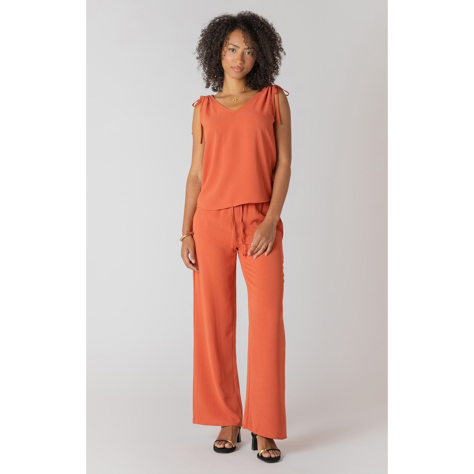 Model wearing Room 34 V-Neck Top with Shoulder Ties in orange, sleeveless with adjustable shoulder ties.