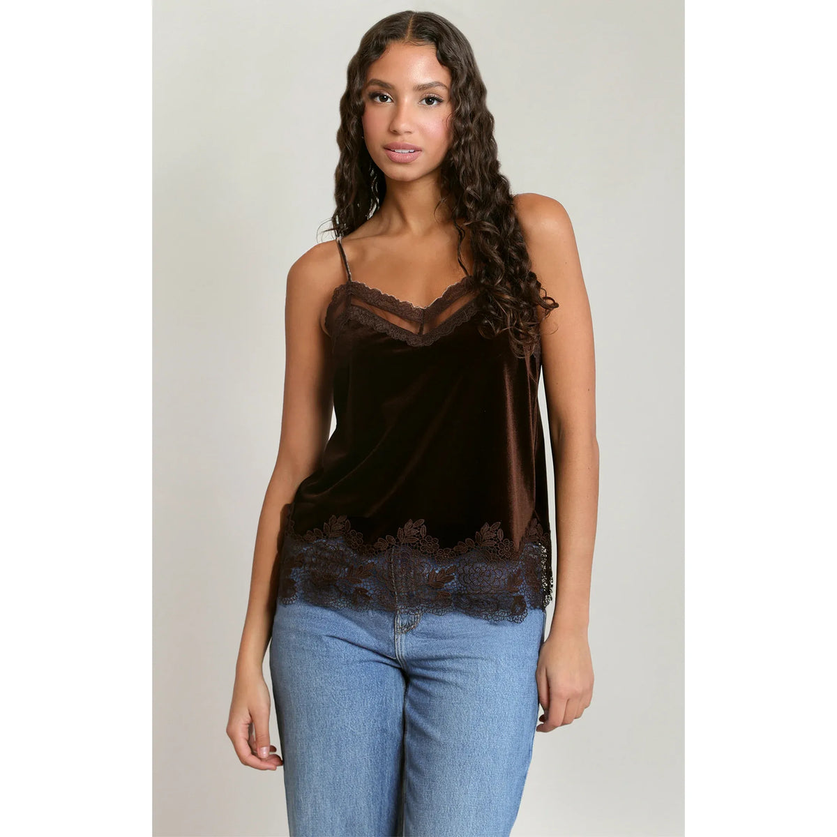 Model wears dark chocolate velvet camisole with lace trim at neckline and hem, paired with blue jeans.