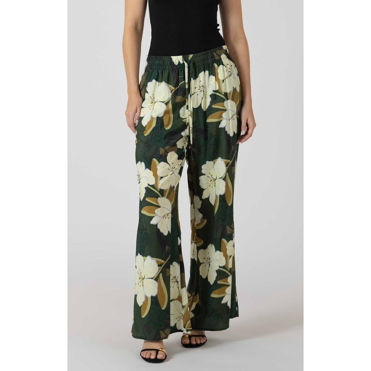 Dex Wide Leg Flowy Pants with large white florals on dark green, elastic waistband, worn with a black top.