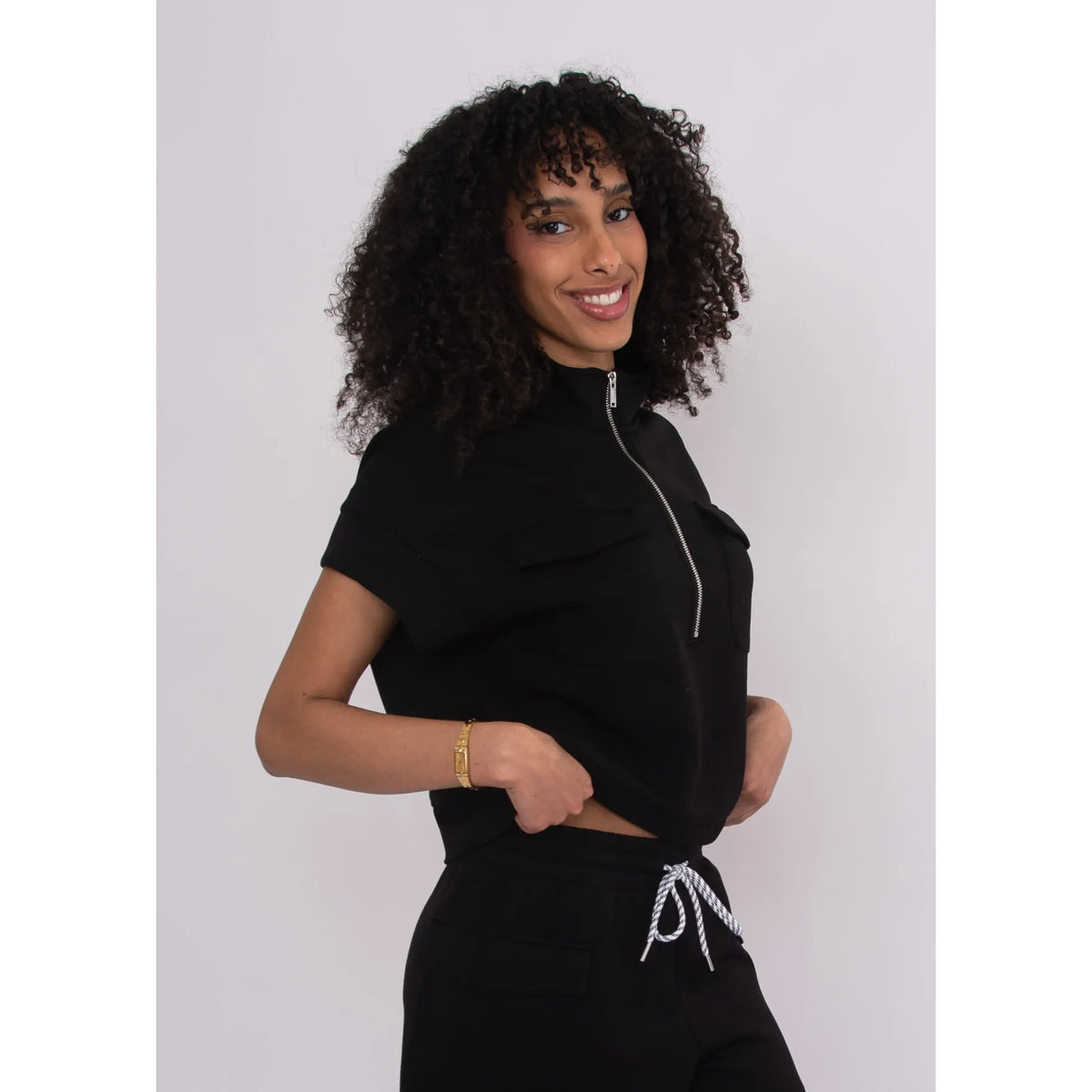 Model wearing Dua Soft Knit 1/2 Zip Top in black with short sleeves and relaxed fit.