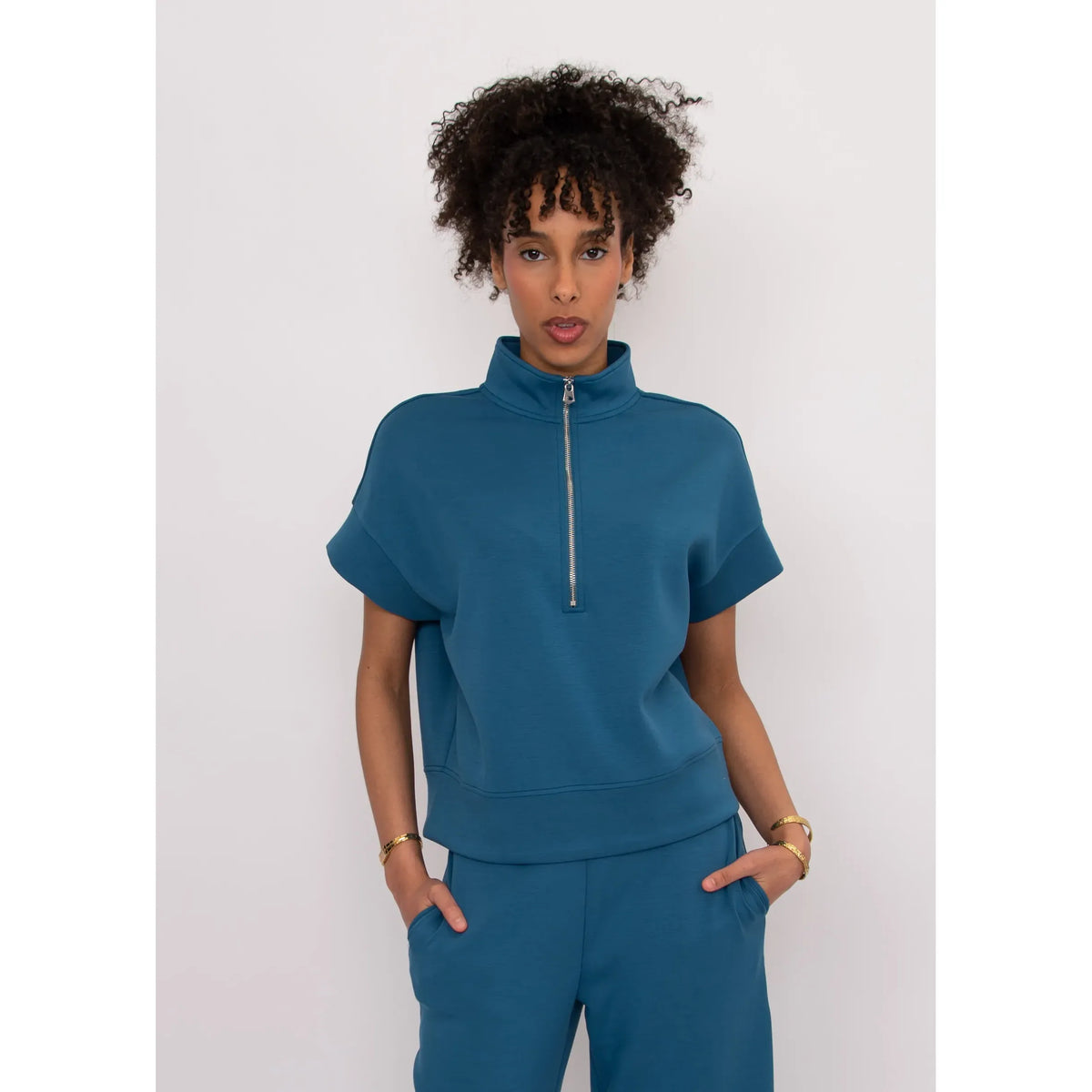Dua Soft Knit 1/2 Zip Top in teal with short cuffed sleeves and relaxed fit, zip front worn by a model.