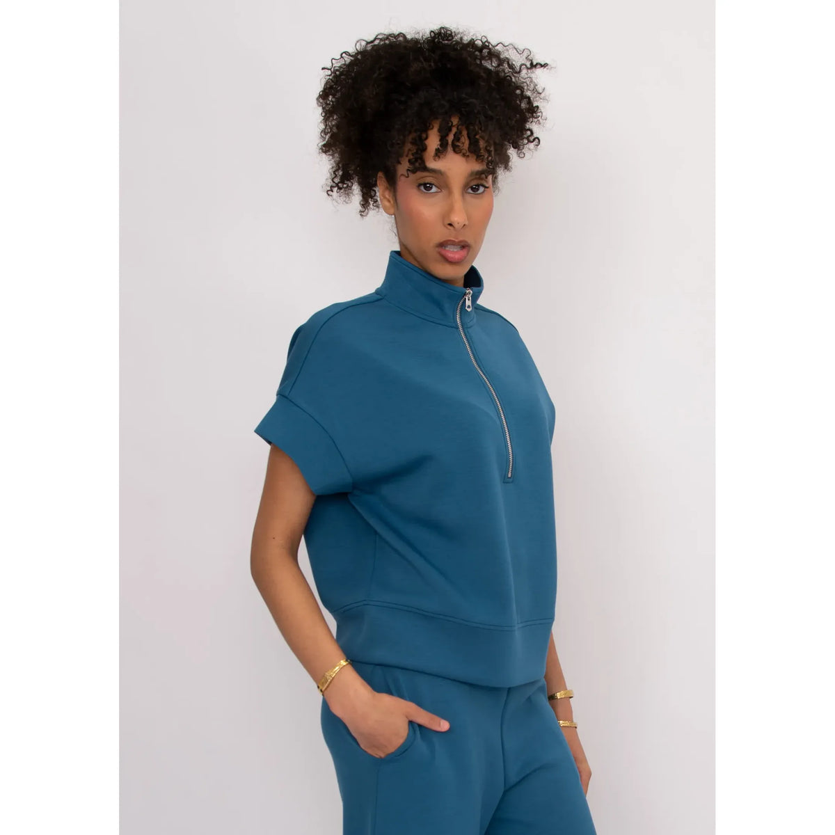 Dua Soft Knit 1/2 Zip Top in teal with short cuffed sleeves on a model; breezy, relaxed fit.