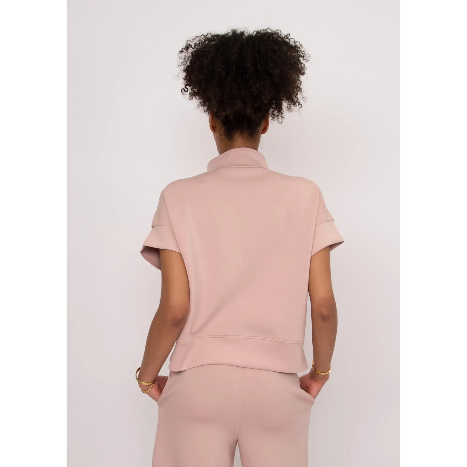 Back view of a model in a pink Dua Soft Knit 1/2 Zip Top with short cuffed sleeves.
