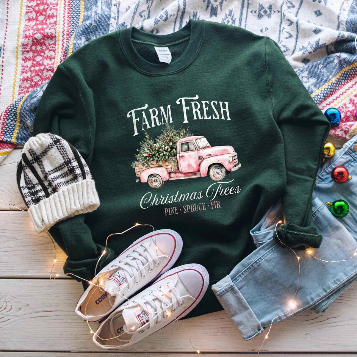 Dark green "Farm Fresh Christmas Trees" crewneck featuring a vintage pink truck graphic, styled with white sneakers and a beanie.